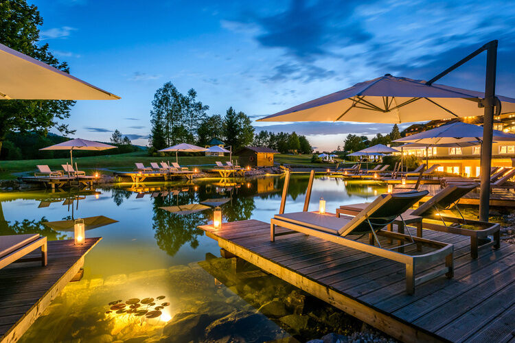 Beleuchteter Naturbadesee in Abenddämmerung