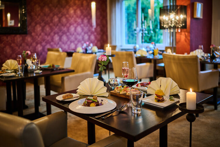 Elegant gedeckte Restauranttische mit Kerzenlicht und Gourmetgerichten.