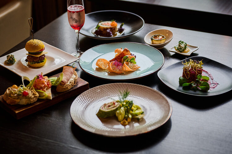 Vorspeisenvariation auf schwarzen und weißen Tellern, kunstvoll angerichtet mit Deko.