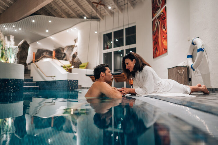 Eine Frau entspannt am Rand eines Swimmingpools im Wutzschleife-Wellnesshotel.