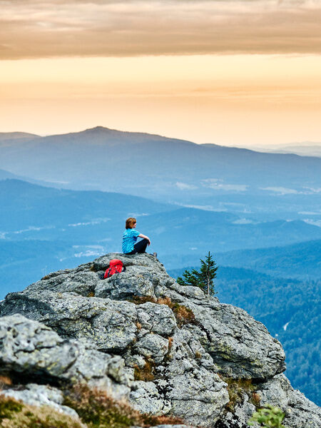 Frau sitzt am Berg bei Sonnenaufgang