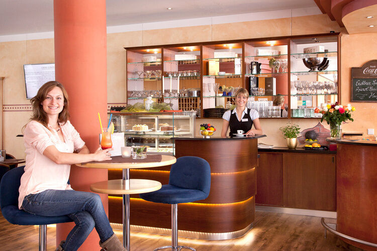 Frau sitzt mit Cocktail an der Hotelbar