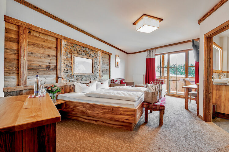 Ein großes Bett mit Holzmöbeln in einem stilvoll eingerichteten Schlafzimmer im Tonihof.