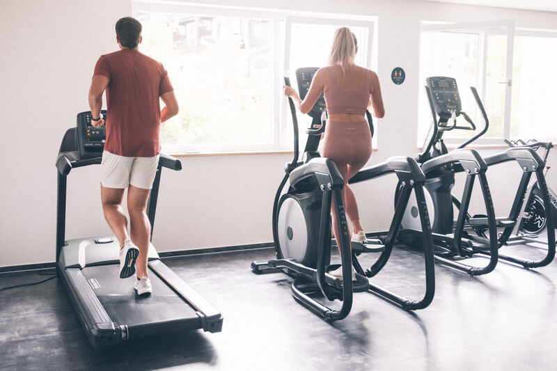 Mann und Frau auf Trainingsgeräten im Fitnessraum