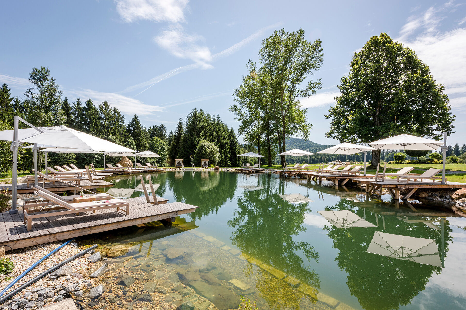 Traumhafter Naturbadesee mit Liegestegen und Sonnenliegen bei Sonnenschein