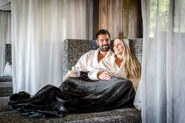Paar entspannt auf einer Sofa-Liege und genießt Erfrischungsgetränke im 4-Sterne-Hotel Hüttenhof