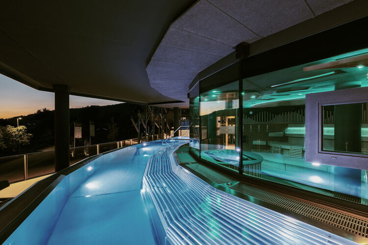 Der blau beleuchtete FKK Skypool vor der eindrucksvollen Architektur des Hotels Tonihof.