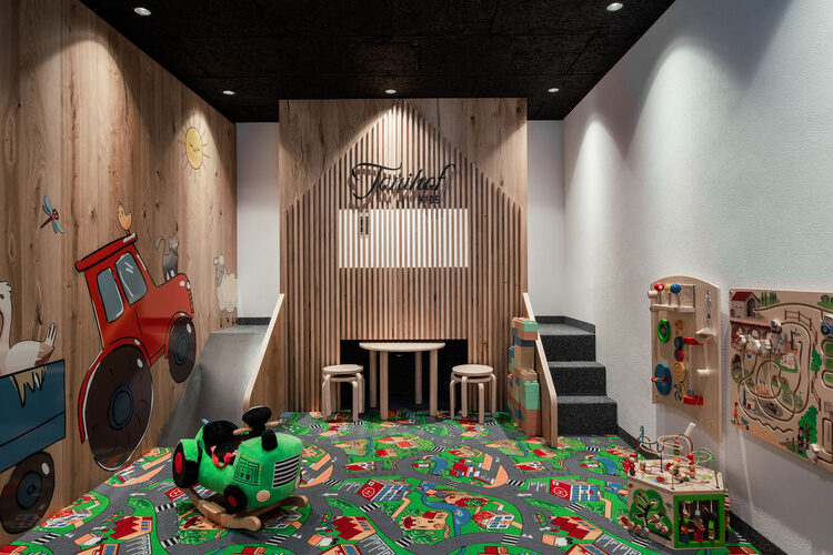 Ein fröhliches Kinderzimmer im Tonihof mit vielen Spielsachen auf dem Boden.