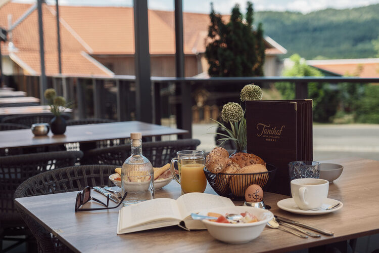 Ein gedeckter Tisch im Freien des Tonihof mit weißem Geschirr und blauen Details.