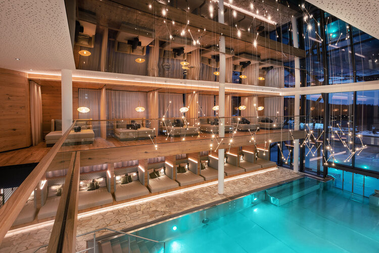 Der modern gestaltete Innenpool des Tonihof im Bayerischen Wald wird von gemütlichen Liegen umrahmt und bietet durch ein großes Fenster direkten Zugang zum Außenbereich.