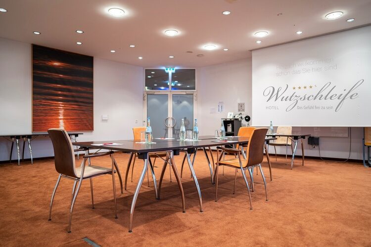 Ein Konferenzraum im Hotel Wutzschleife mit eleganten Tischen und Stühlen.