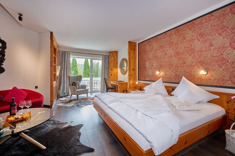 Ein großes Bett mit roten Sofa in einem stilvollen Schlafzimmer der Wutzschleife.