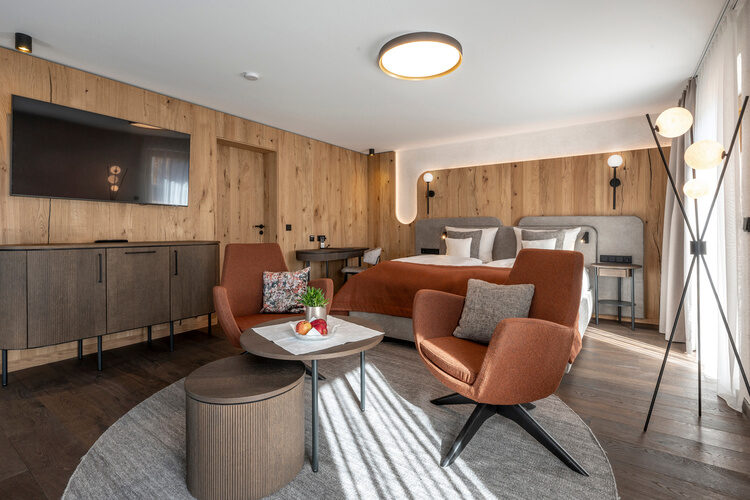 Gro&szlig;r&auml;umiger Wohnbereich mit strahlender Beleuchtung und Flachbildfernseher - Zimmer Typ 3 im Hotel Mooshof in Bayern.